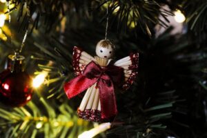 Close-up of a handmade Christmas angel ornament hanging on a festive tree branch.